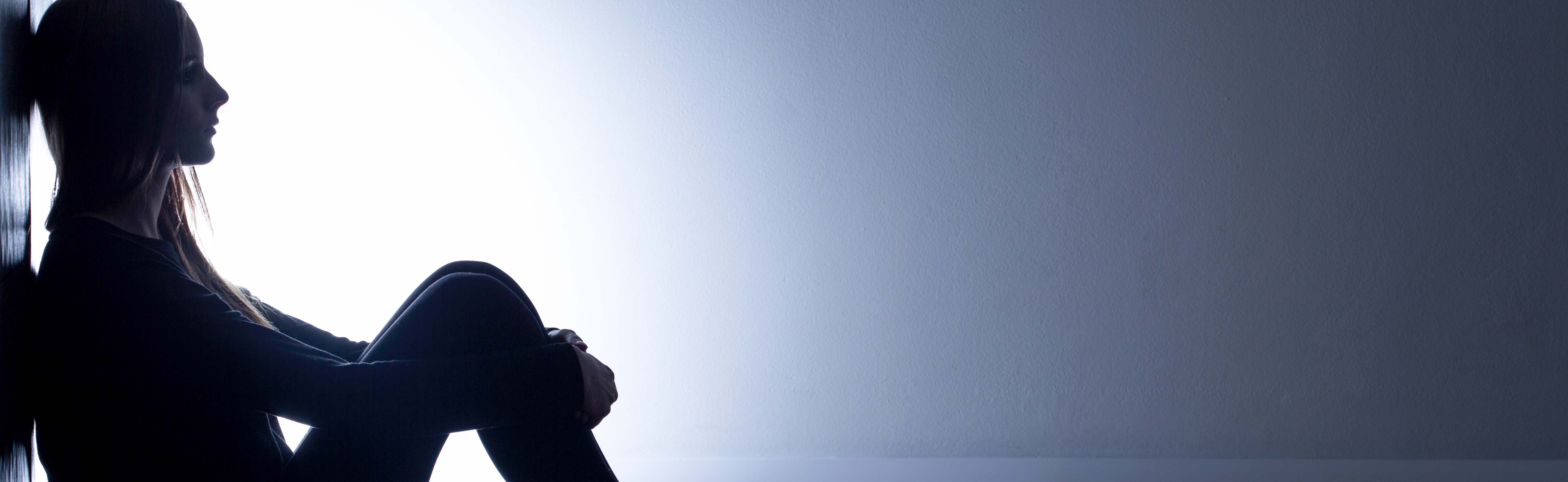 Teenage girl sitting with her back against a wall
